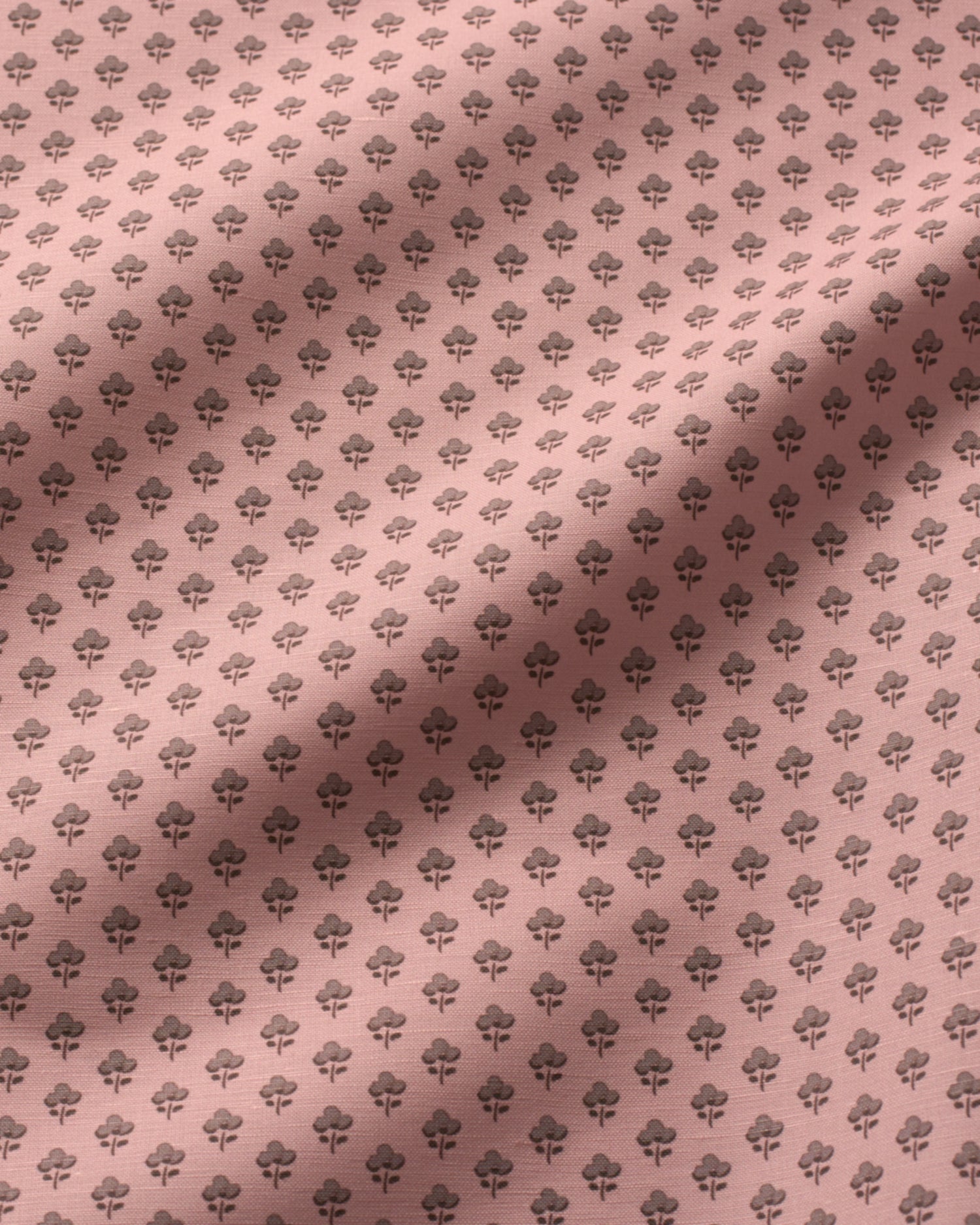 A close-up of a dusty pink fabric with a repeating dark gray floral or rose pattern, featuring soft diagonal shadows across the surface.